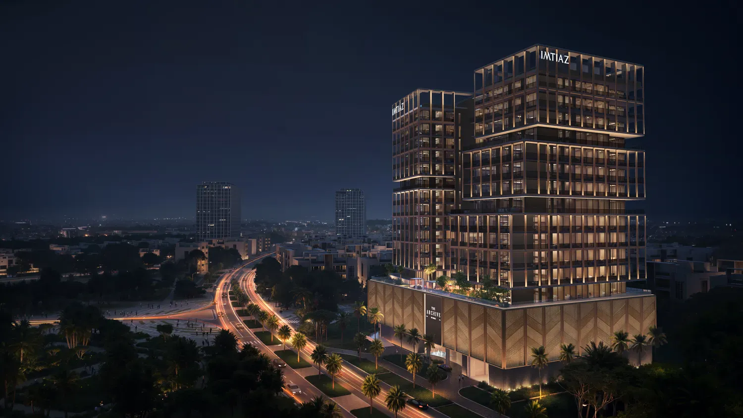 The Archive lit at night beside the road into Dubailand Residence Complex